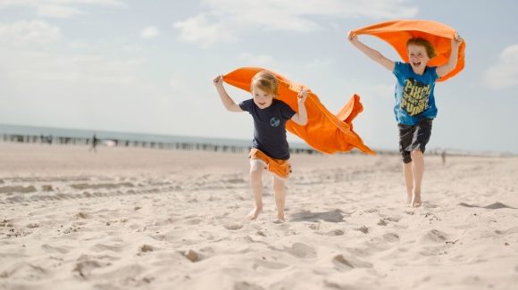 jongens met oranje handoeken rennen over het strand high rgb 6716