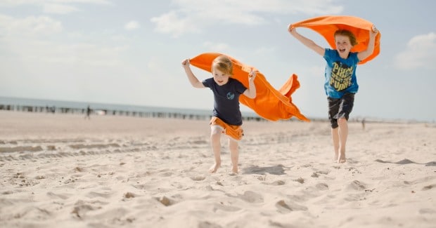 jongens met oranje handoeken rennen over het strand high rgb 6716