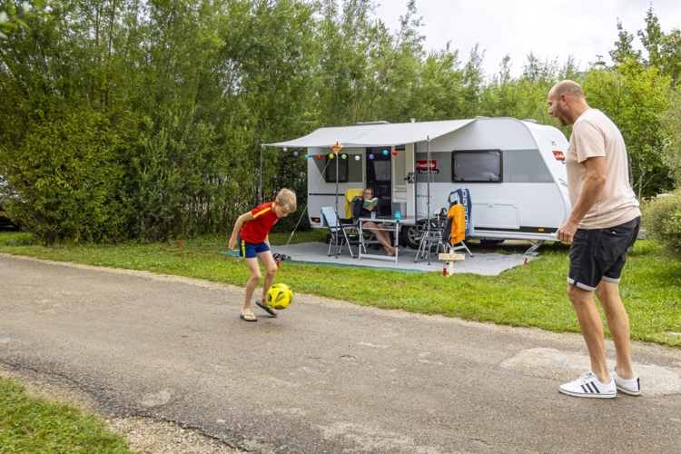 TestTour Jura 2023_testteam Gezinskampeerders_camping La Roche d’Ully_Gerbrand en Sam voetballen voor de caravan